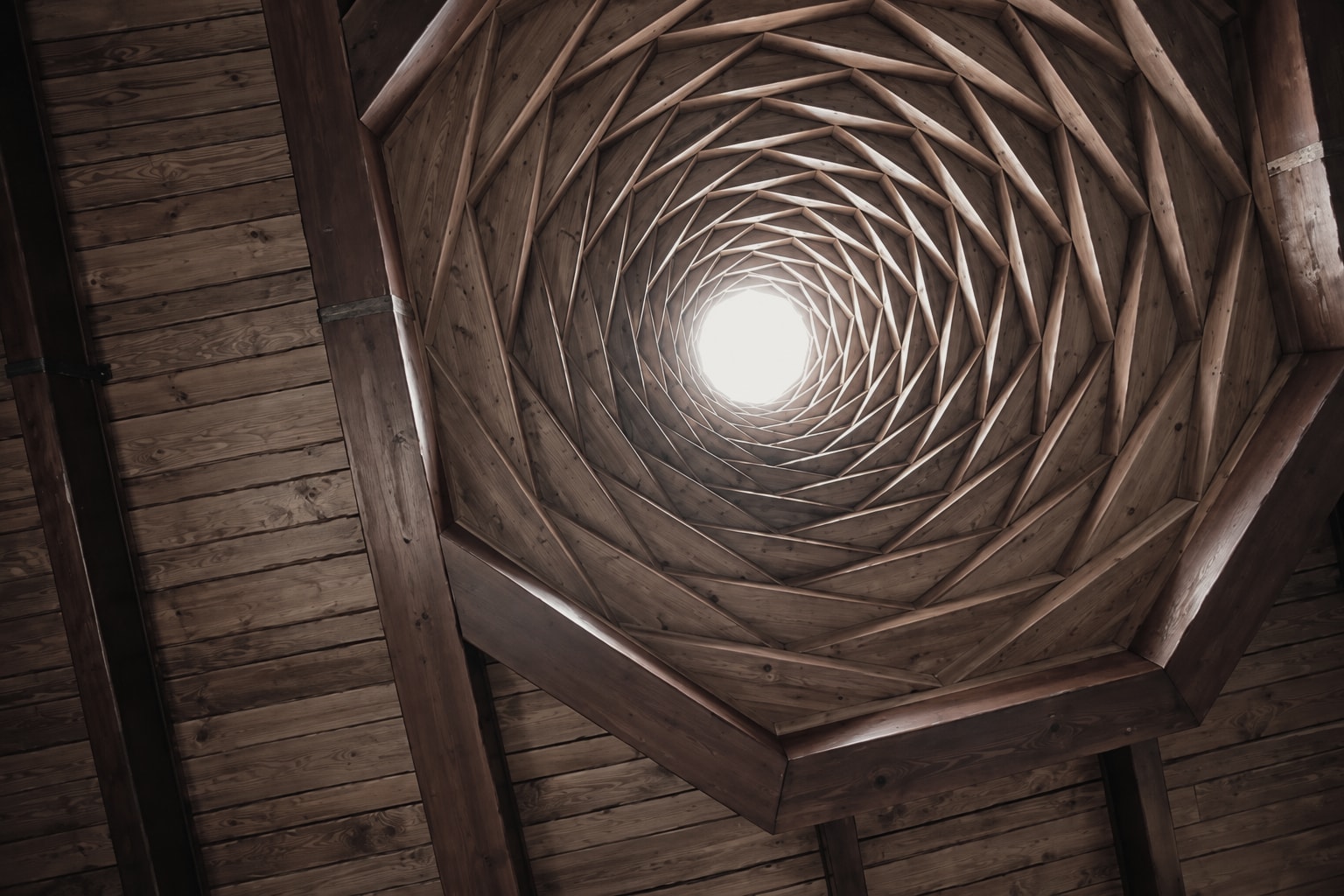A wooden dome ceiling spiralling up to a skylight